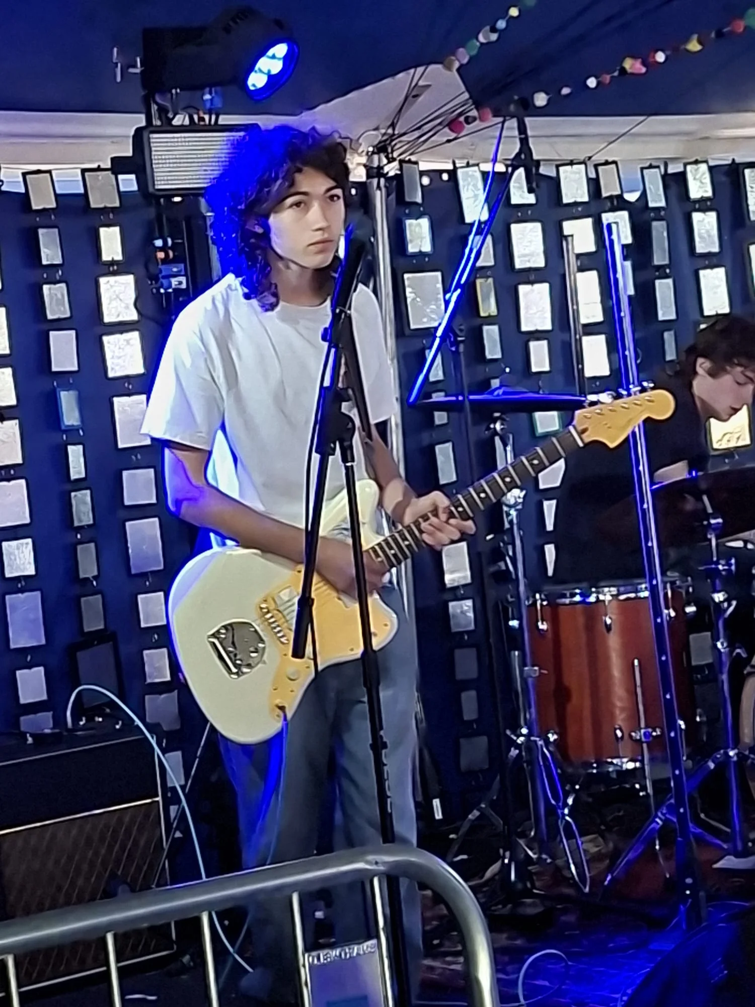 An Aphid guitarist and drummer performing under blue stage lighting
